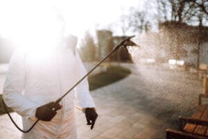 Man in virus protective suit and mask disinfects public places. Infection prevention and control.